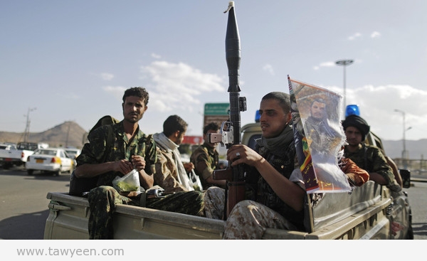 Houthi fighters holding weapons ride on the back of a patrol truck in Sanaa